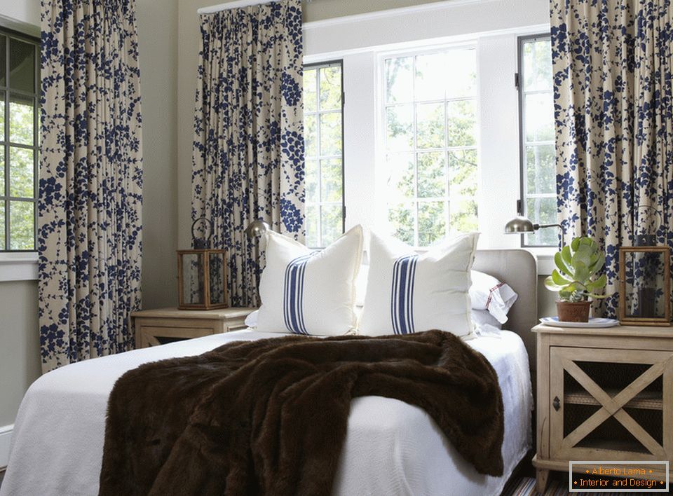 Fiori blu sulle tende e strisce sui cuscini sono armoniosamente combinati all'interno della camera da letto