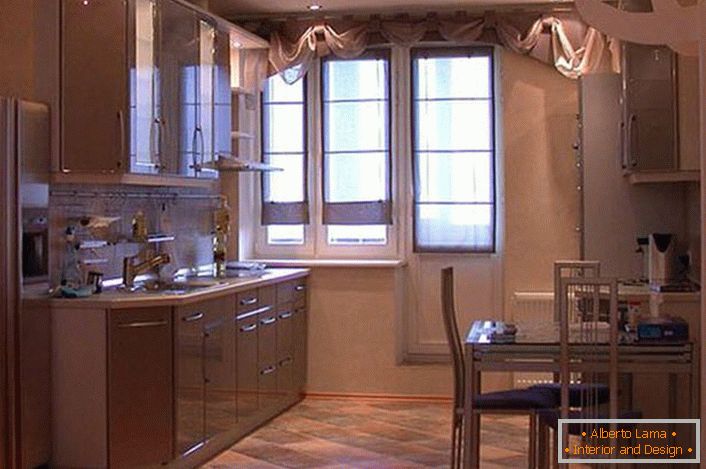 Una cucina spaziosa con armadi sospesi in tonalità beige chiaro sembra attraente e squisita. Invece di una dispensa, il progettista fece una nicchia, dove per comodità fu messo un frigorifero.
