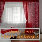 Tende rosse, cuscini e tappeti in combinazione con pareti bianche e mobili