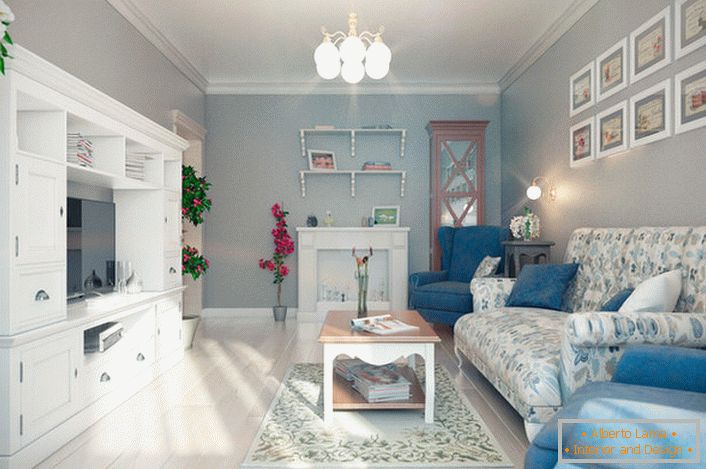 Le poltrone blu a contrasto si abbinano perfettamente al parquet chiaro. Il muro sopra il divano è decorato in modo interessante con dipinti delle stesse dimensioni.
