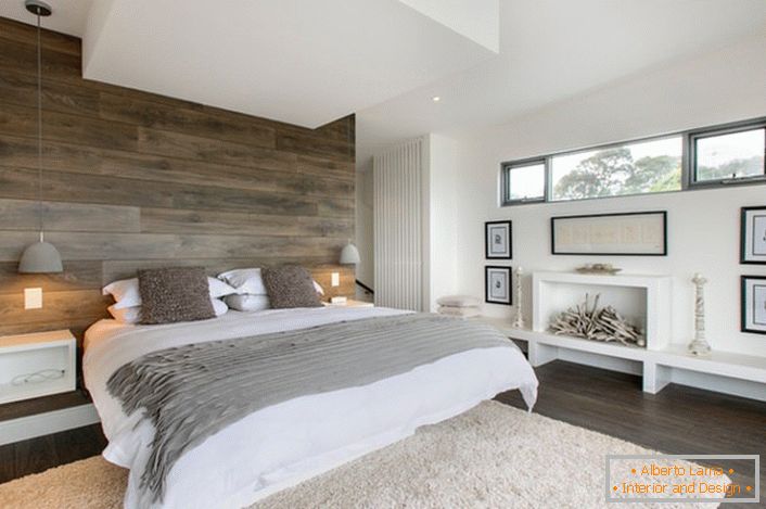 Una camera da letto elegante in campagna rustica. Lo spazio progettato dal punto di vista funzionale non è ingombro di dettagli superflui. La camera da letto è l'esempio giusto di una casa di famiglia.