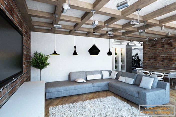 Accogliente soggiorno luminoso in stile loft. Combinazione armoniosa di pareti in mattoni in muratura e travi massicce. 
