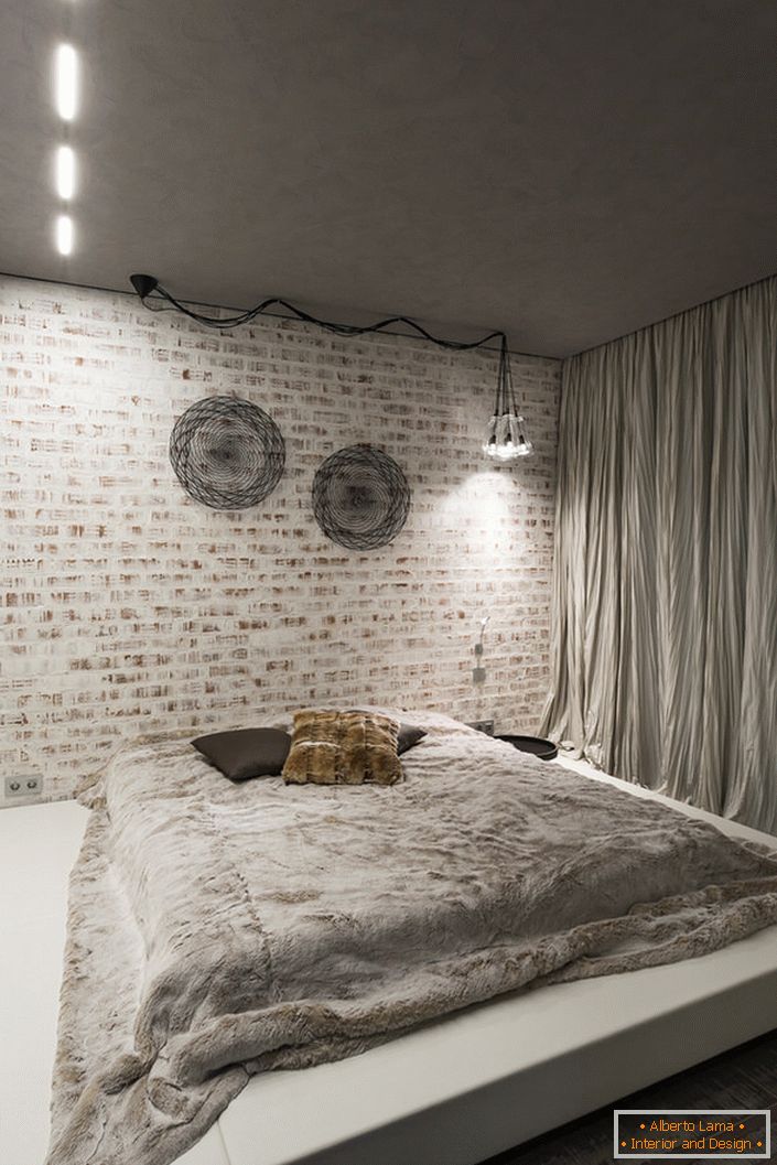 La camera da letto in stile loft deve contenere al suo interno un minimo di mobili. Una buona scelta per questo concetto di stile è un grande letto morbido su un basso podio.