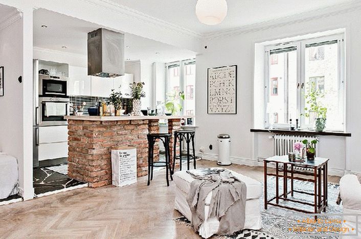 L'appartamento monolocale è decorato in stile scandinavo. La cucina è separata dal soggiorno da un bancone in mattoni.
