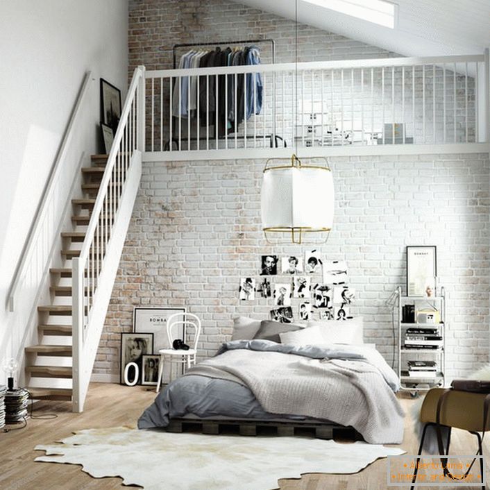 La camera da letto in stile scandinavo è funzionalmente divisa in due zone. Una scala in legno conduce al secondo piano, dove c'è un piccolo spogliatoio sul letto.
