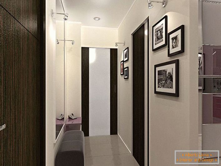 Soluzione di design per un corridoio stretto. La decorazione a contrasto dei colori bianco e marrone scuro, non solo sembra elegante, ma rende anche visivamente più la stanza.