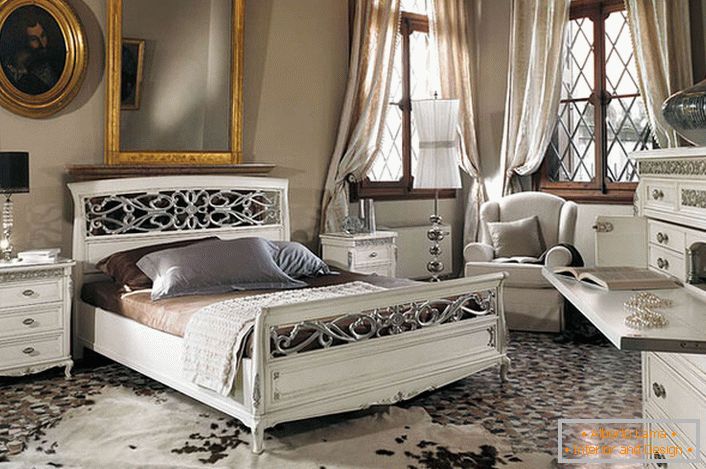 Si osserva il requisito di base dello stile barocco. In una spaziosa camera da letto con soffitti alti, mobili in legno bianco contrasta con le cornici delle finestre scure.