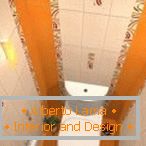 La combinazione di piastrelle bianche e arancioni nel design della toilette