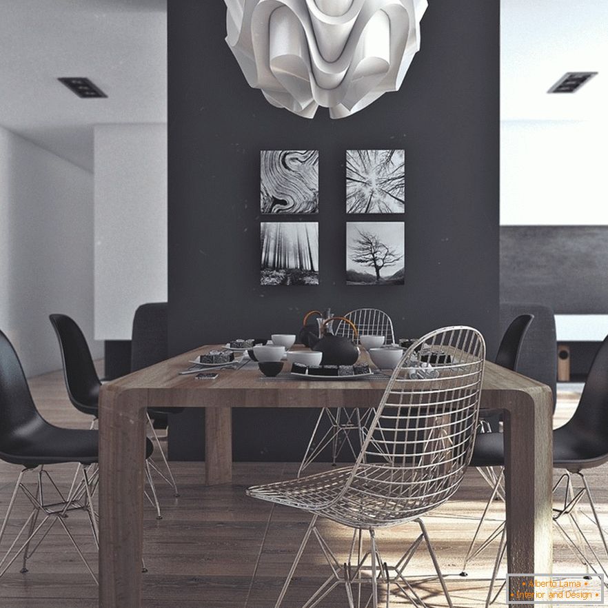 Un tavolo da pranzo in legno, sedie nere e dipinti originali su un muro nero