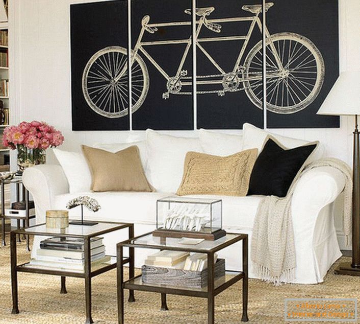 Il soggiorno in stile scandinavo è decorato con dipinti modulari raffiguranti una bicicletta. Non sovraccarico di significato, il design rende il design completo. 