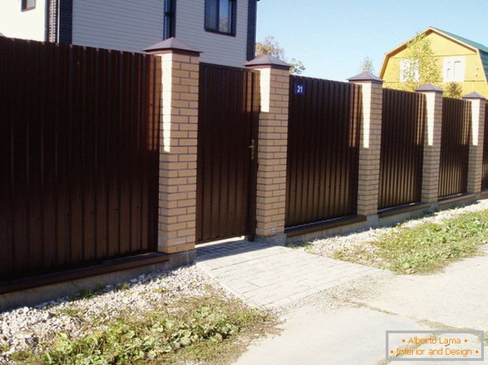 La recinzione modulare è marrone scuro con una finitura in mattoni - un classico del genere, se parliamo del design delle aree suburbane.