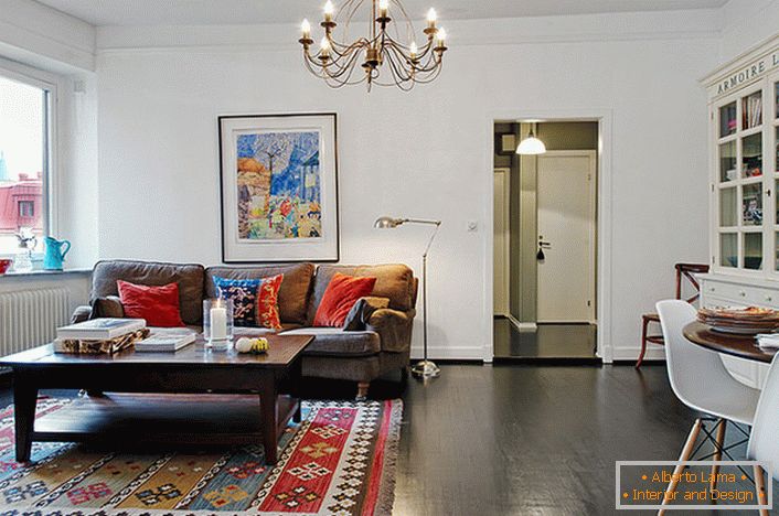 Un'elegante camera per gli ospiti in un tipico appartamento di città è decorata con cuscini luminosi sul divano e sul tappeto. 