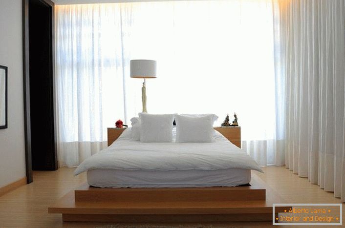 Il letto assomiglia a un grande morbido letto di piume, che si trova su un'alta passerella di legno. Le tende realizzate in morbido tessuto traslucido rendono l'atmosfera nella stanza romantica e rilassante. 