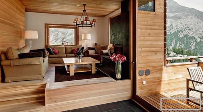 Il piano mansardato della villa con accesso alla veranda è decorato nello stile di uno chalet. Il colore del legno chiaro sembra vantaggioso in combinazione con una piastrella marrone scuro.