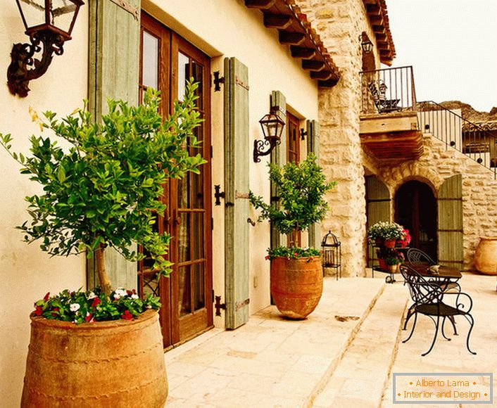 Il patio в средиземноморском стиле украшают горшки с живыми растениями. Привлекательный дизайн, мебель с витиеватыми спинками, керамические горшки создают уютную, расслабляющую атмосферу. 