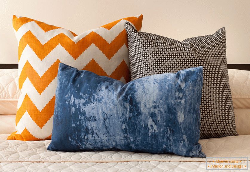 Cuscini decorativi di colore arancione, blu e bianco e nero con stampe interessanti sul letto