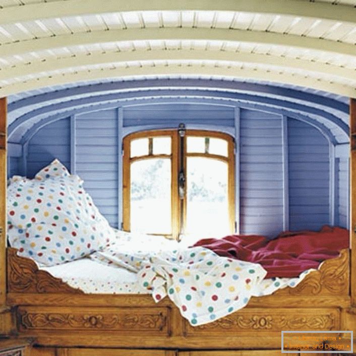 Minimi dettagli in camera da letto in stile rustico. Il designer ha scelto una posizione insolita per il letto. Un lettino alla finestra è il letto perfetto per i sognatori.
