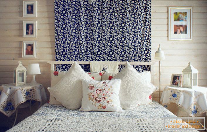 In conformità con lo stile rustico, il letto è decorato con un numero di cuscini con ricamo rosso a contrasto. I comodini sono ricoperti da una tovaglia con delicati fiori blu.