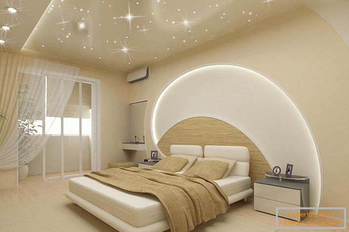 L'attenzione attrae la decorazione delle pareti e del soffitto della camera da letto in uno stile moderno. Strisce LED passano attraverso il soffitto e il muro sopra il letto, i soffitti tesi imitano il magico cielo stellato.