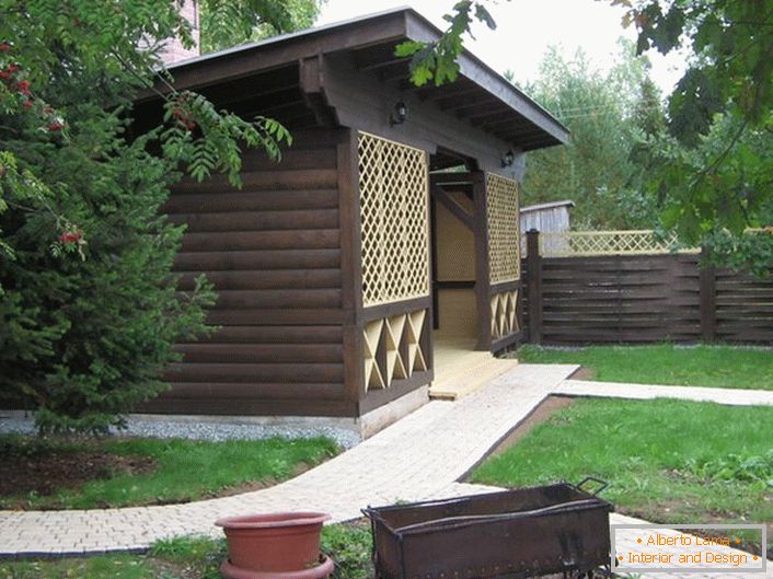 Un gazebo scuro in legno nello stile di uno chalet è una scelta popolare per i moderni proprietari immobiliari suburbani.