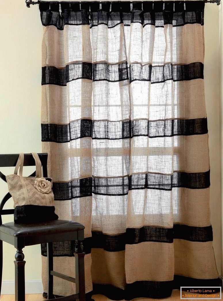 Una sedia vicino alla finestra con le tende di tela di sacco