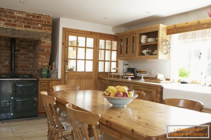 Ampia cucina in stile country. I mobili in legno e le decorazioni in mattoni sopra la stufa conferiscono uno stile naturale e romantico.