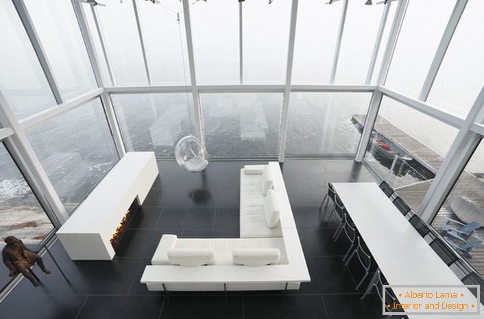 Design laconico del salotto in stile minimalista. Un pezzo interessante di arredamento è una sedia sospesa da un soffitto alto.