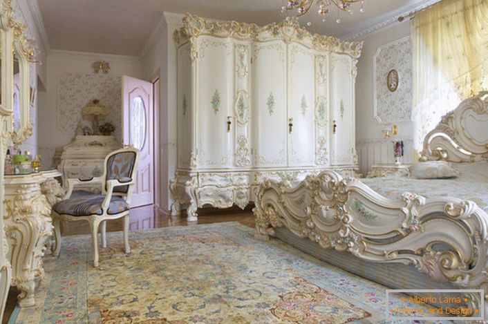 Camera da letto bianca come la neve con mobili massicci scolpiti in legno. Il letto con testata alta sulla testiera, si inserisce elegantemente nell'interno in stile barocco.