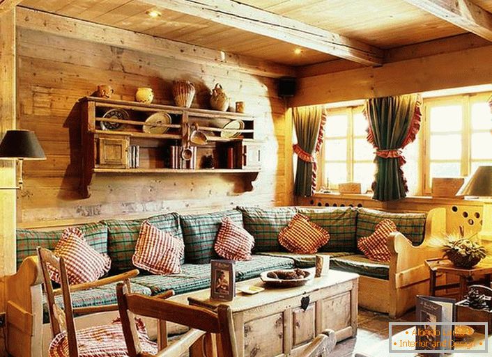 Decorazione della parete in legno, cuscini a contrasto su un morbido divano, tende con volant sulle finestre. Salotto accogliente in stile rustico in una casa di campagna.