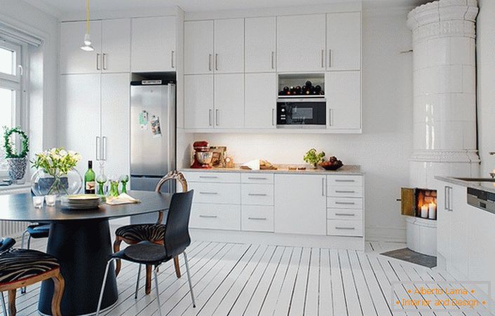 Camino piastrellato, fatto con piastrelle di ceramica bianca, si inserisce organicamente all'interno della cucina in stile scandinavo.