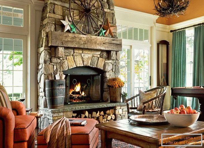 Una spaziosa camera per gli ospiti in una casa di campagna in stile country. Notevoli sono le grandi finestre con cornici in legno e un enorme camino, realizzato in pietra naturale.