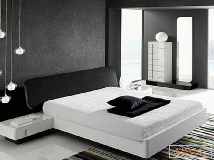 Il muro alla testata del letto, decorato con un inserto grigio opaco, secondo lo stile dell'hi-tech è in armonia con il pavimento bianco lucido.