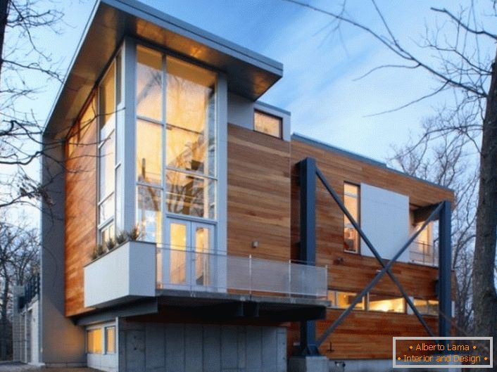 Le pareti in legno della casa sono in stile high-tech con eleganti finestre panoramiche in plastica.