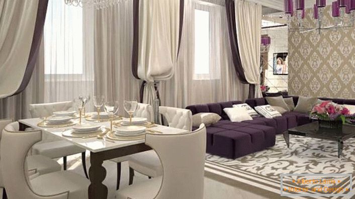 Tende pesanti alle finestre in combinazione con morbidi mobili bianco-lilla si combinano per ricreare l'interno in stile art deco. In base allo stile, anche l'illuminazione è selezionata. Il lampadario a soffitto è decorato con le stesse tonalità lucide di viola scuro.