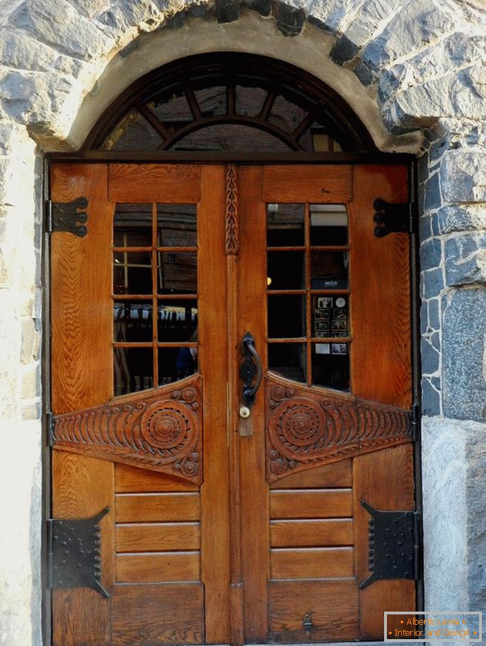 Le porte in stile Art Nouveau decorano la porta d'ingresso di un cottage di campagna con una facciata in pietra naturale. 