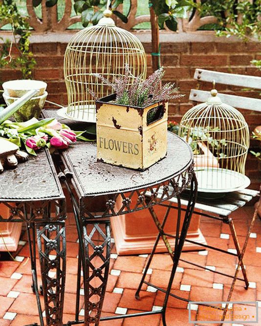 Tavolo forgiato, scatole con fiori e gabbie per uccelli