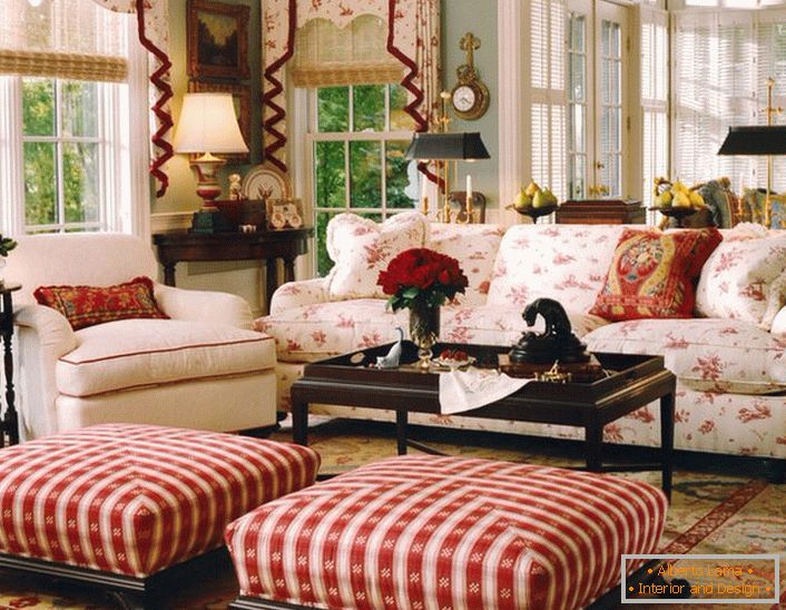 Un semplice, modesto e accogliente soggiorno in stile inglese in una piccola casa di campagna. Gli accenti di rosso rendono l'atmosfera nella stanza rilassata e allegra.