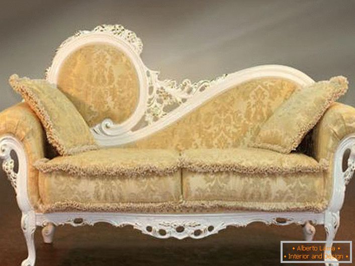 Lo schienale intagliato del divano e il morbido rivestimento beige con un ornamento appena percettibile nella migliore tradizione del barocco.