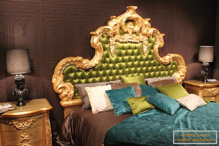 Un alto schienale ornato nella testa del letto è ricoperto di seta olivastra. Cuscini interessanti di colori contrastanti e copriletti sul letto.